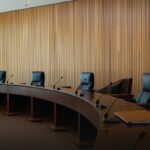 Mesa de julgamento vazia em plenário de tribunal administrativo, com microfones e pastas de documentos, onde o CARF julga teses como a do JCP extemporâneo