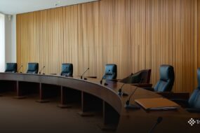 Mesa de julgamento vazia em plenário de tribunal administrativo, com microfones e pastas de documentos, onde o CARF julga teses como a do JCP extemporâneo