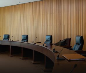 Mesa de julgamento vazia em plenário de tribunal administrativo, com microfones e pastas de documentos, onde o CARF julga teses como a do JCP extemporâneo